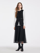 A lady wears a black tulle skirt and boots.
